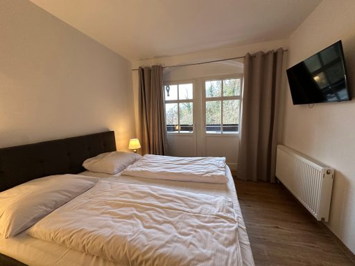 Gemütliches Schlafzimmer mit zwei Betten, Fenster und modernem Fernseher.